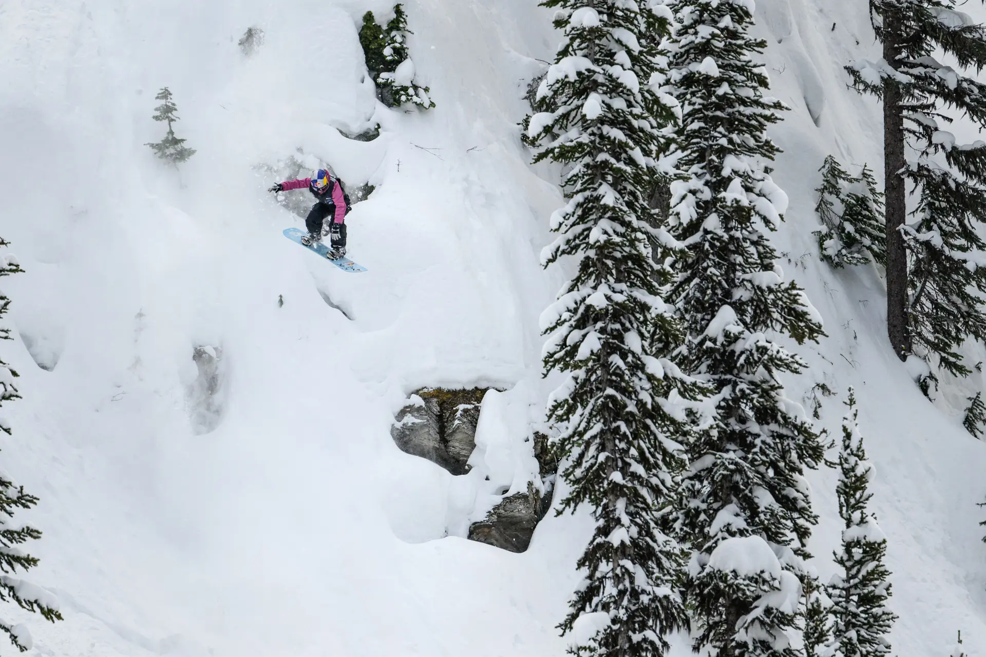 a snowboarder navigating a steep snow-covered slope
