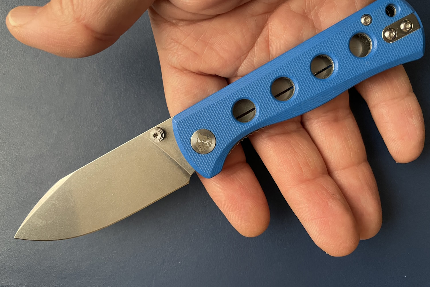Hand holding QSP Canary knife with a blue handle