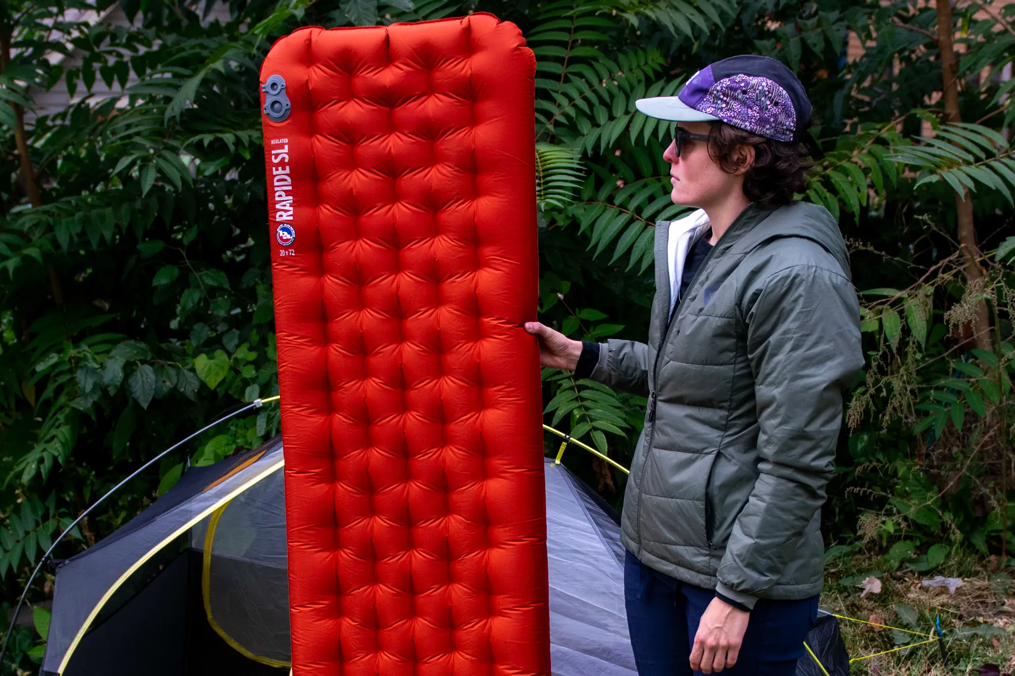 A person holds the Big Agnes Rapide SL insulated sleeping pad to demonstrate its size in relation to their height