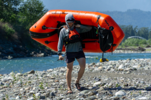 A packrafter carries the NRS Neutron over his shoulder beside the Chilliwack River