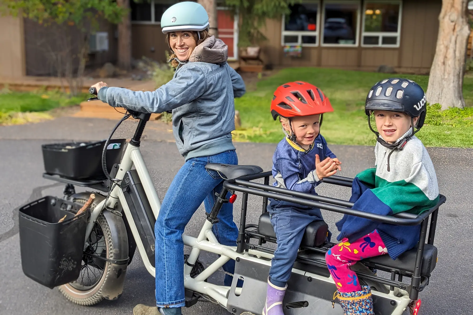 A tester riding the Specialized Globe Haul LT electric cargo bike with two child passengers on the back