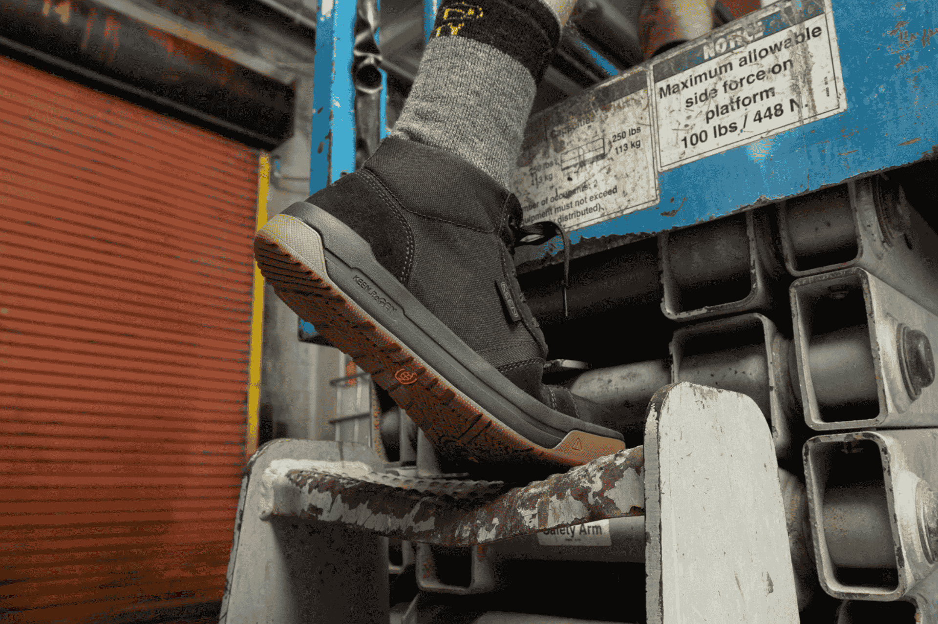 Person stepping on steel ladder with KEEN Kenton boot