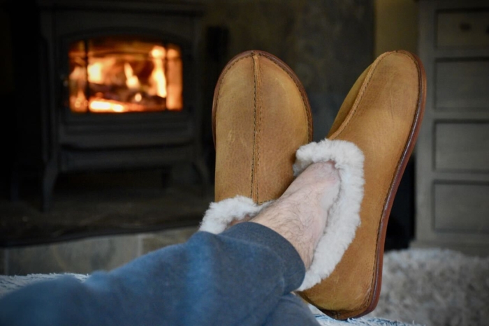a man's cozy feet in the Saddleback Leather Sheepskin Maccasins in front of a wood burning stove