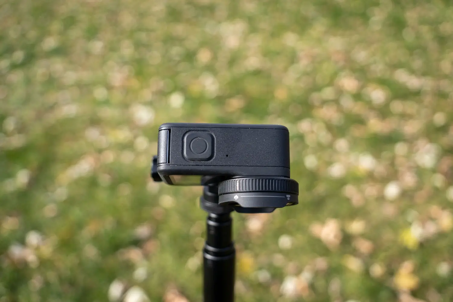 A GoPro camera mounted on a tripod, featuring its side button and a lens filter attachment