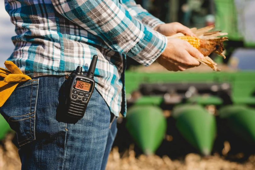 midland radio on jeans pocket with combine in the background
