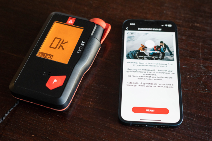 An avalanche beacon shows 'OK' next to a phone running a diagnostic app