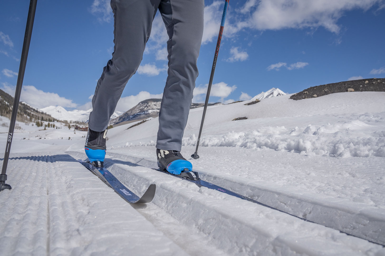 Skis glide along groomed snow tracks under a bright sky
