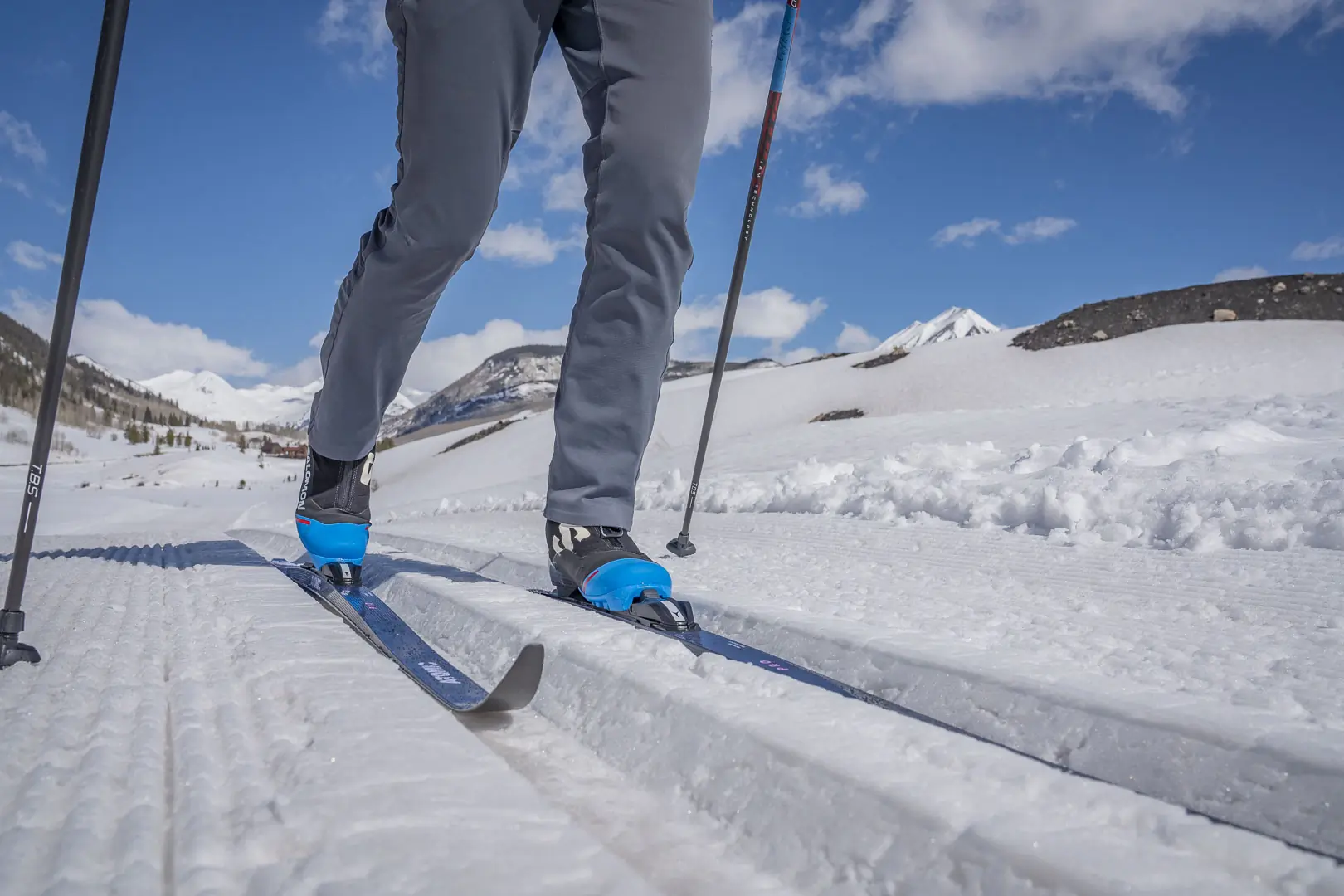 Skis glide along groomed snow tracks under a bright sky