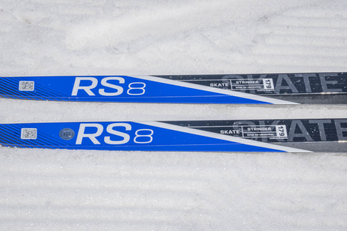 Close-up of Salomon RS8 skate skis on fresh snow, showing blue and gray graphics