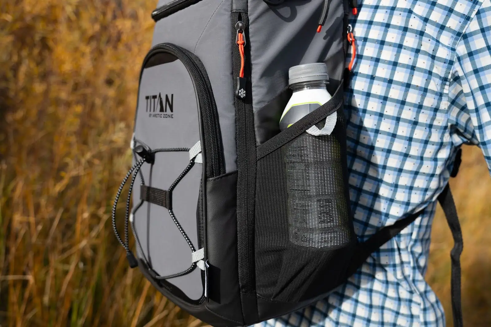 A close-up of a backpack’s mesh side pocket holding a water bottle securely