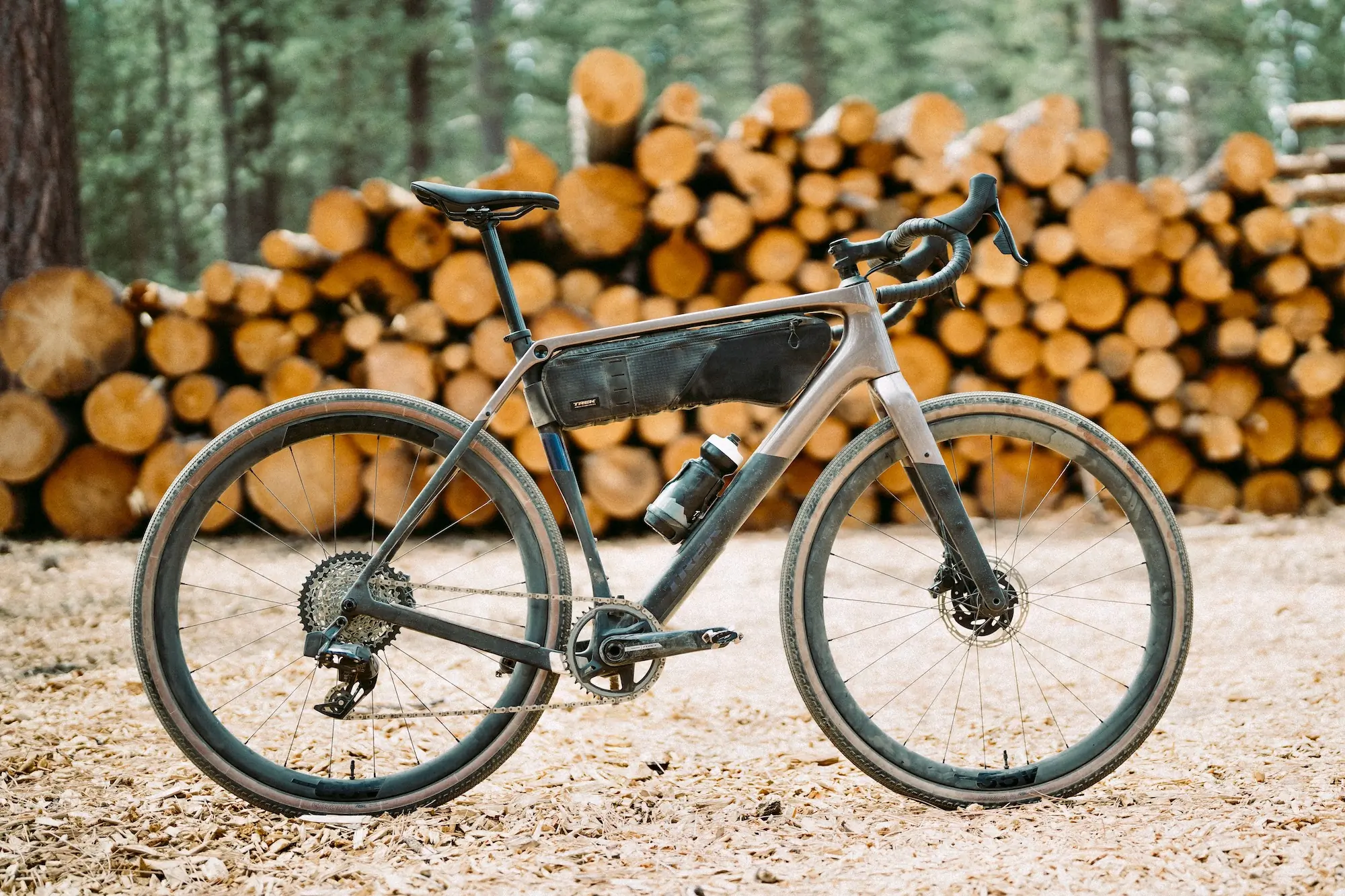 The Trek Checkpoint SL 7 AXS Gen 3 parked in front of a stack of logs in the woods