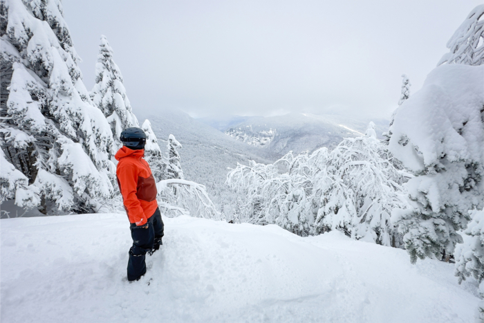 Snowboarder standing on a snowy ridge, showcasing the Arc'teryx Sabre 3L jacket's fit