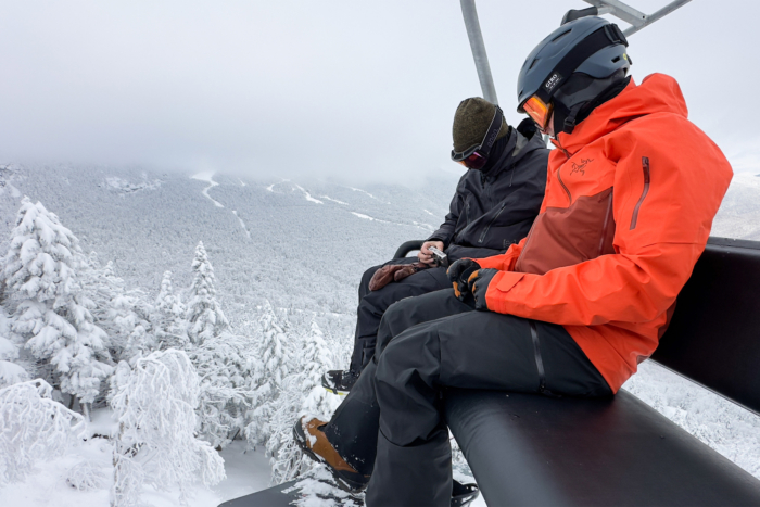Riders on a snowy chairlift, testing the Arc'teryx Sabre 3L jacket in cold mountain conditions