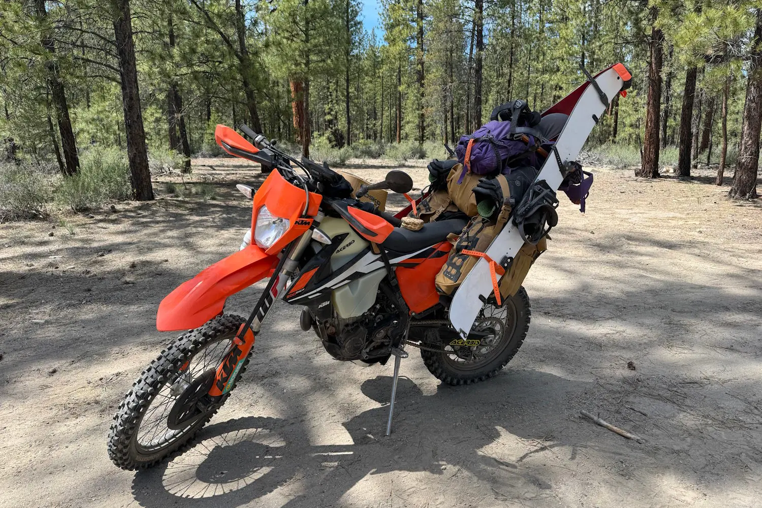 A dirt bike loaded with camping gear and a splitboard