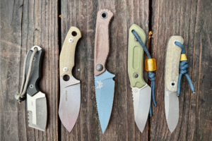 Five fixed-blade knives on a wooden surface