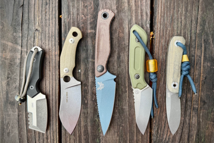 Five fixed-blade knives on a wooden surface