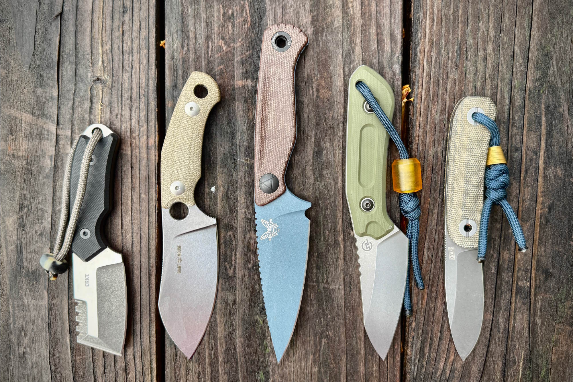 Five fixed-blade knives on a wooden surface