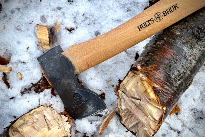 The Hults Bruk Spika axe resting on split wood and snow, highlighting its sharp blade and sturdy handle