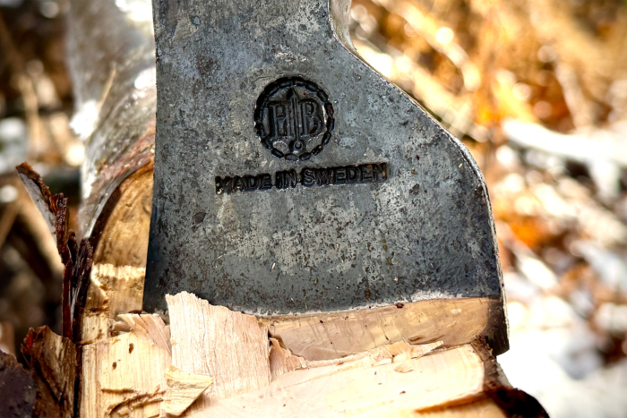 Close-up of the Hults Bruk Spika axe head embedded in wood, highlighting the 'Made in Sweden' engraving