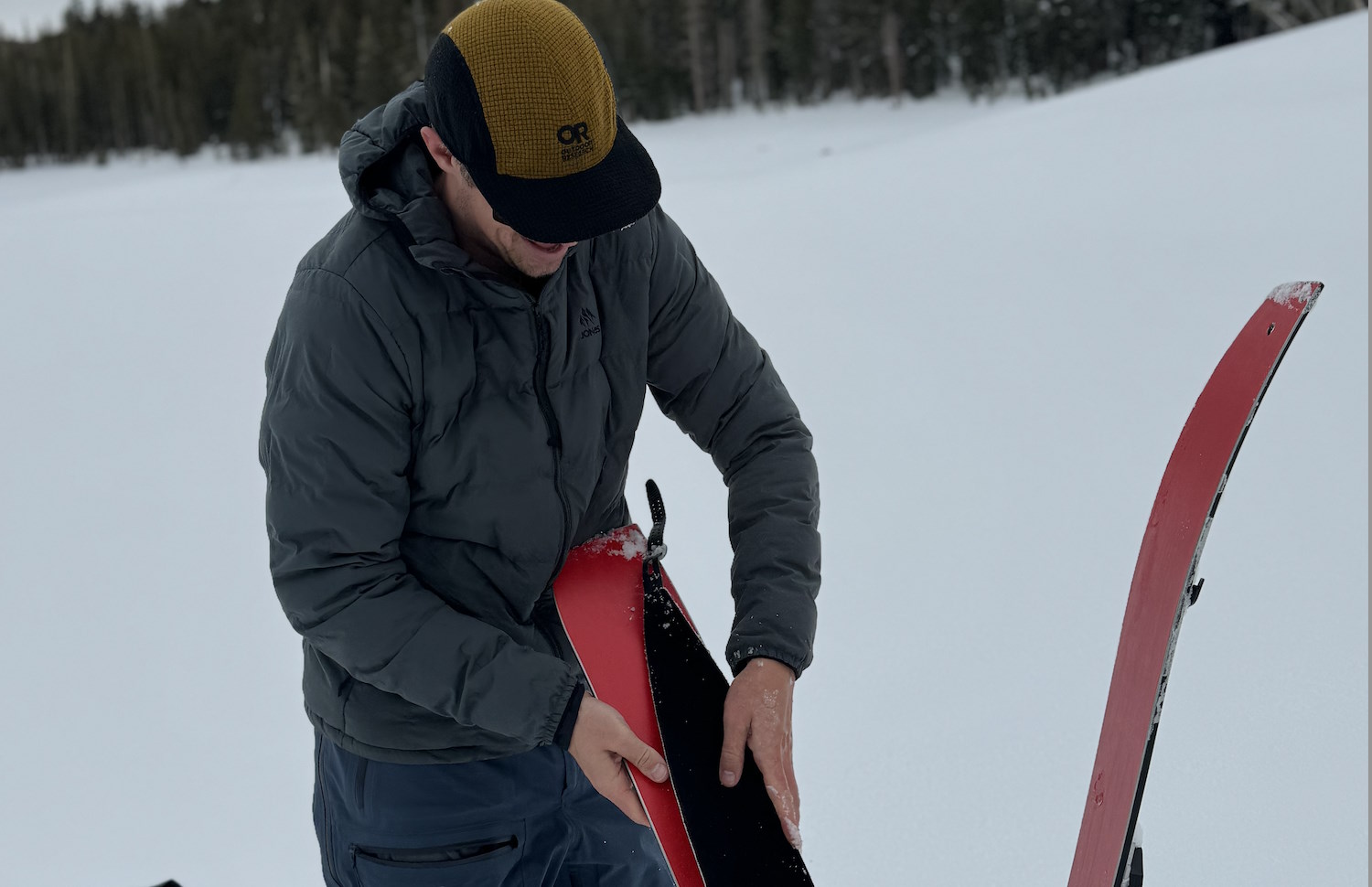 Person attaching skins to a splitboard in a snowy field