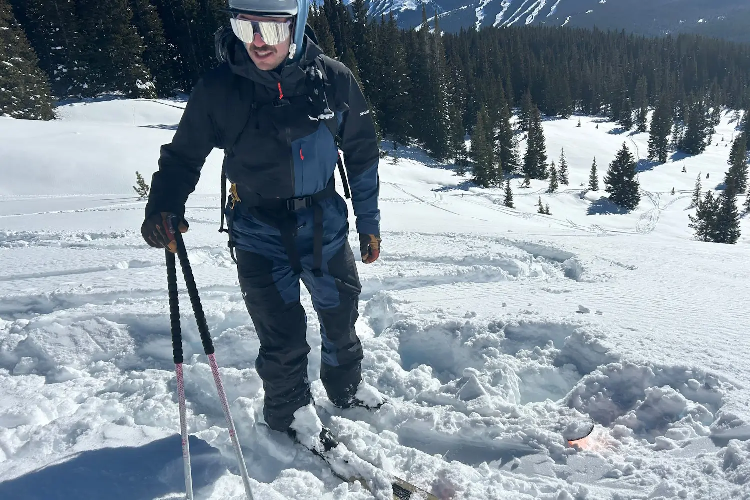 Skier wearing the Sella Free 3L jacket and pants standing in deep snow with ski poles