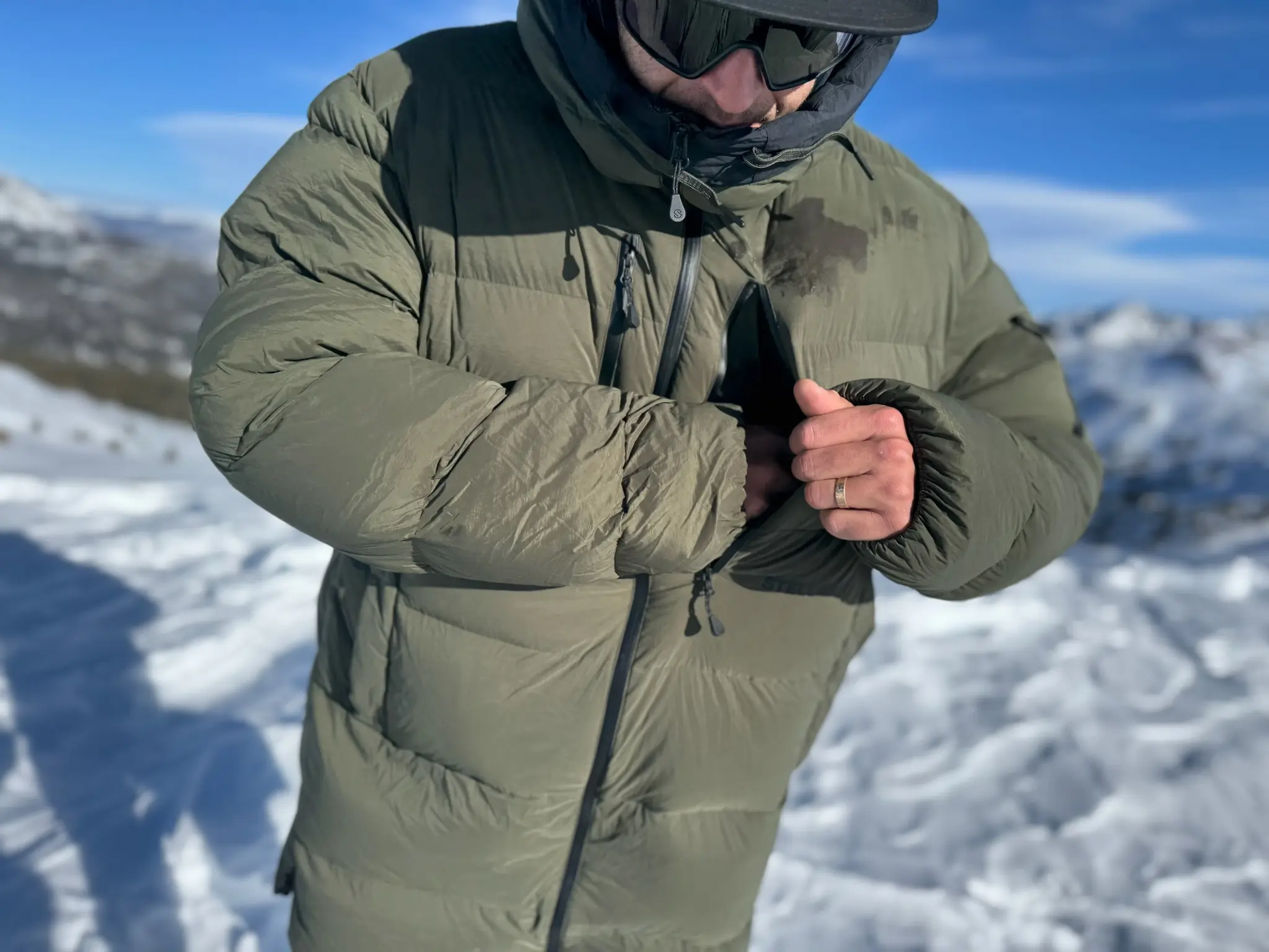 Person adjusting the pocket zipper on the Stellar Free Down Parka