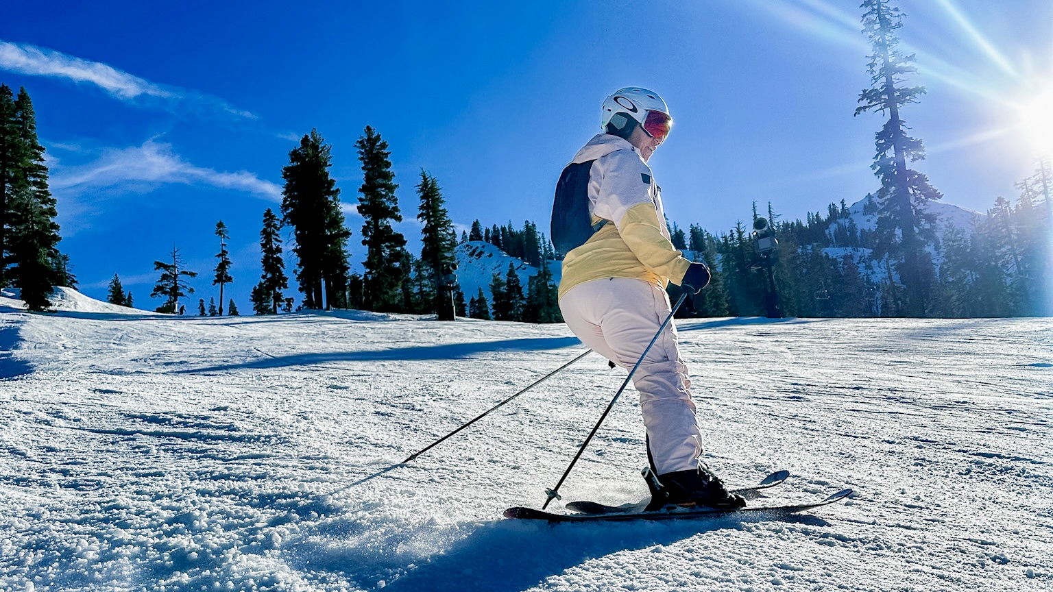 Skier moving with poles on a snowy landscape in Outdoor Research Women's Carbide Bibs