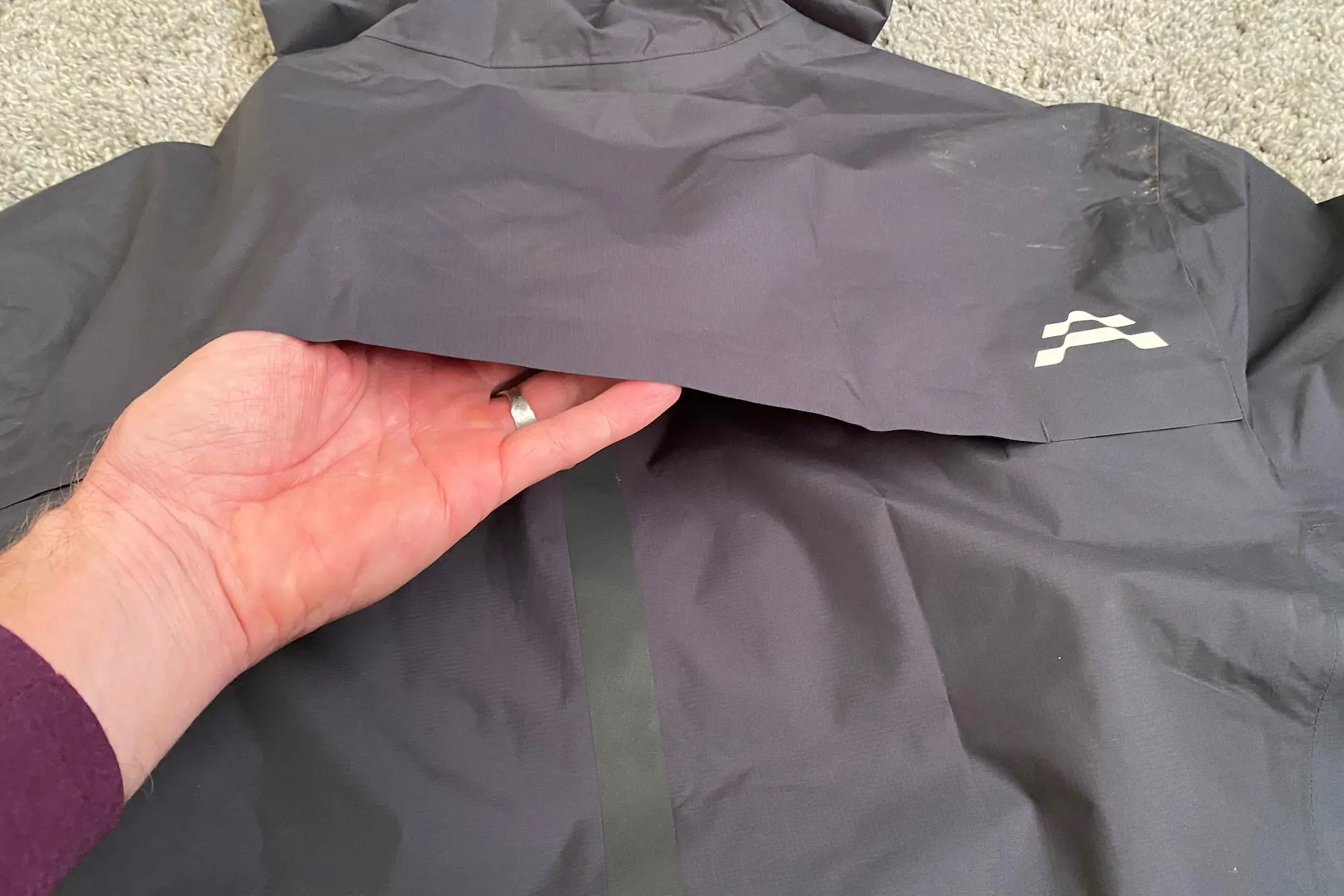 Examining the upper back vent on the Le Col ARC Lightweight Rain Jacket