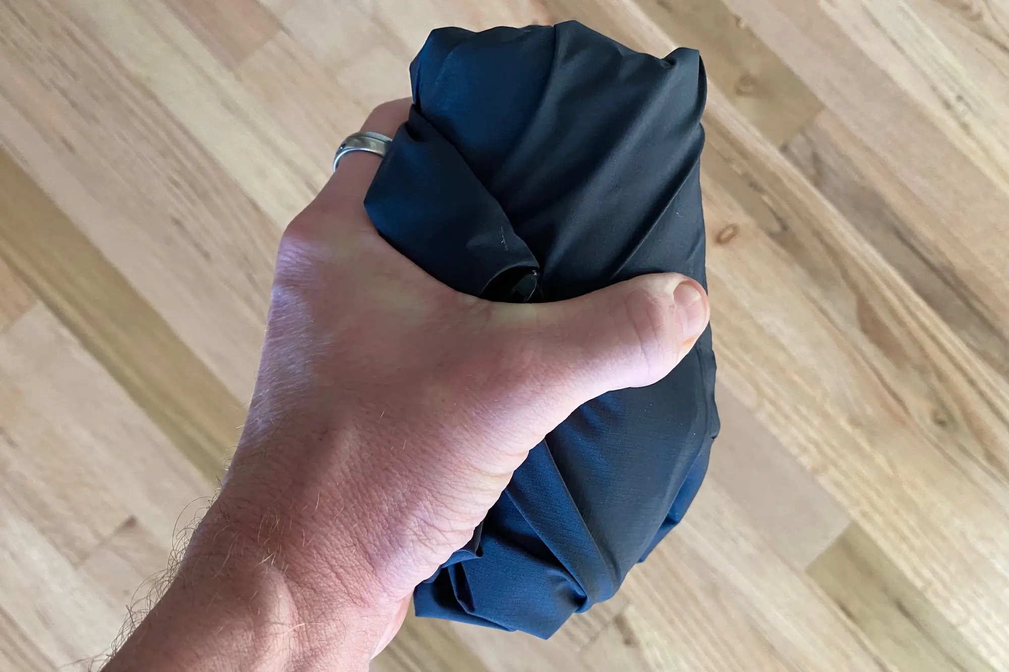 Holding the Le Col ARC Lightweight Rain Jacket in its packed size to demonstrate its packability