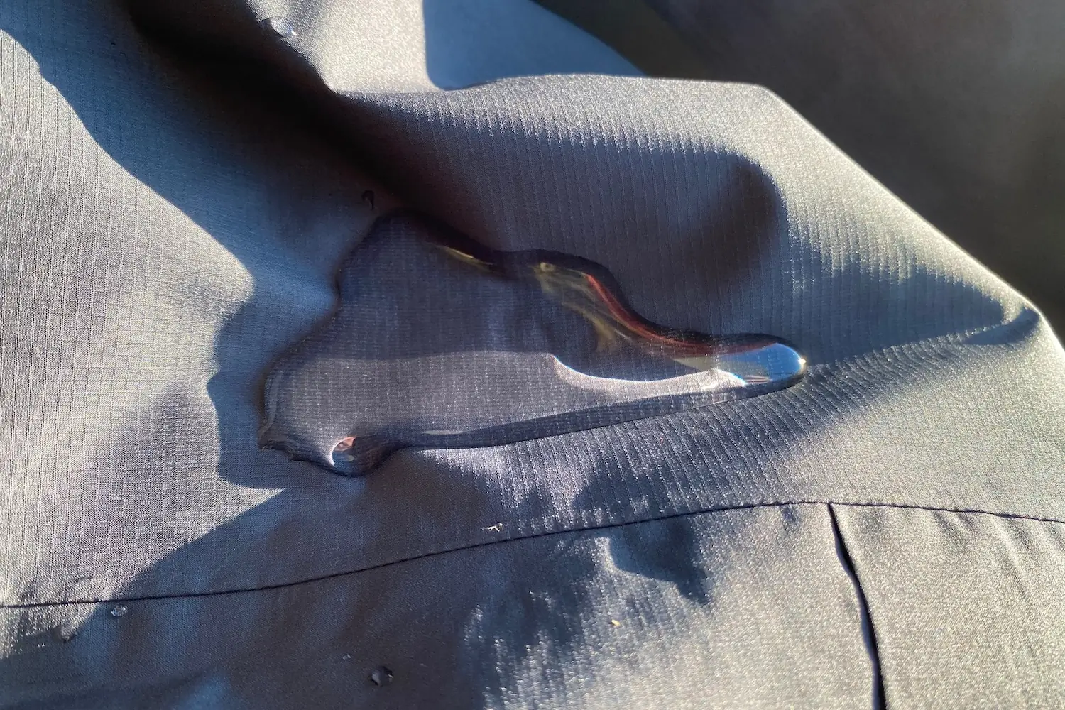 Testing the waterproofness of the Le Col ARC Lightweight Rain Jacket with a small pool of water