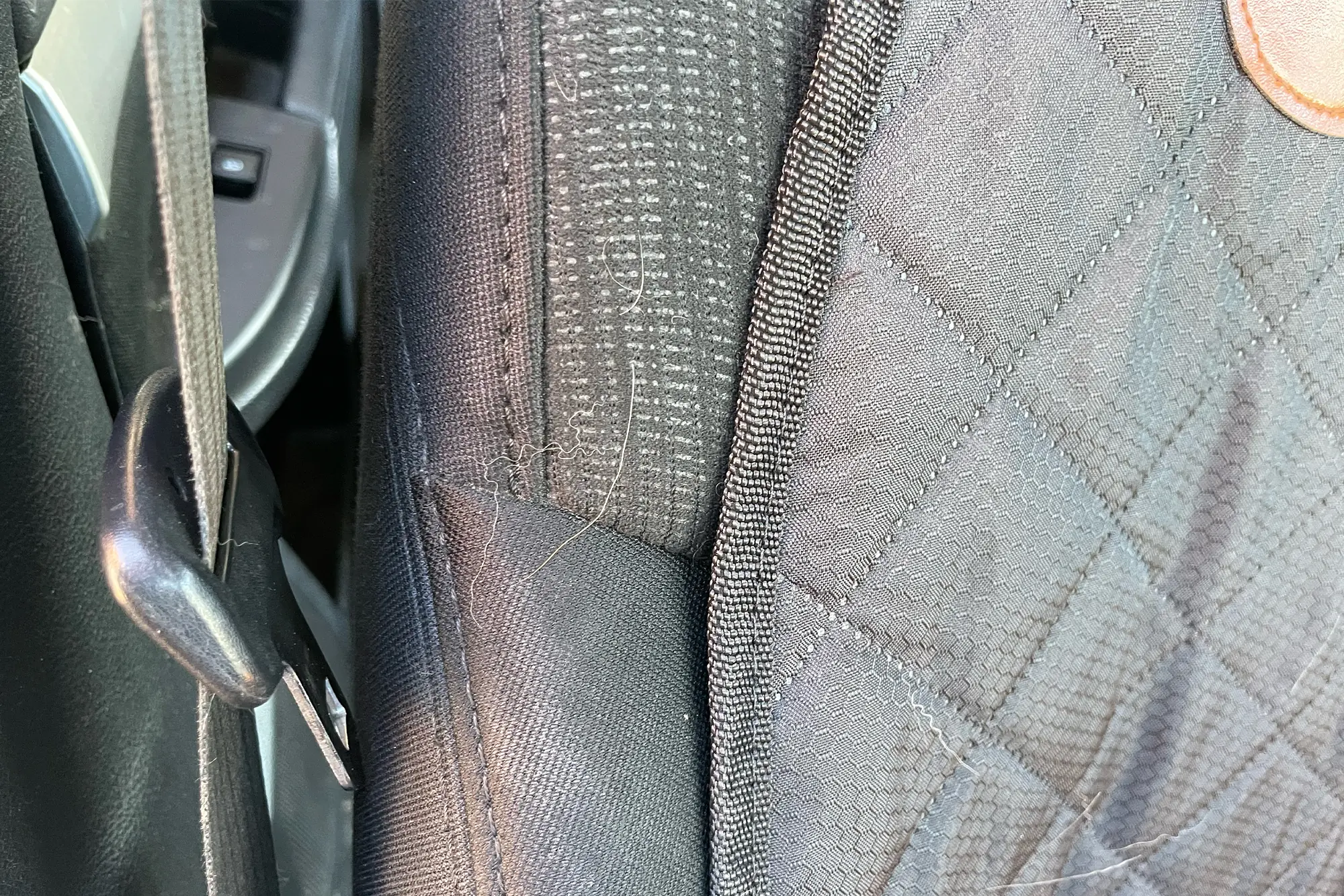 The Paw Jamboree Car Seat Protector does not fully cover the seat corners, allowing dog hair to collect