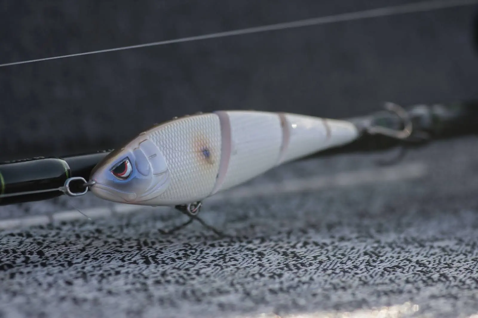 A detailed, jointed fishing lure with a fish-like design, rigged on a fishing rod
