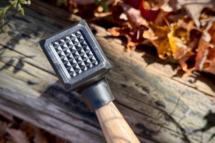 Close-up of the hammer poll of the Hardcore Hammers Camp Companion Axe, showing its textured surface for added grip, with autumn leaves in the background