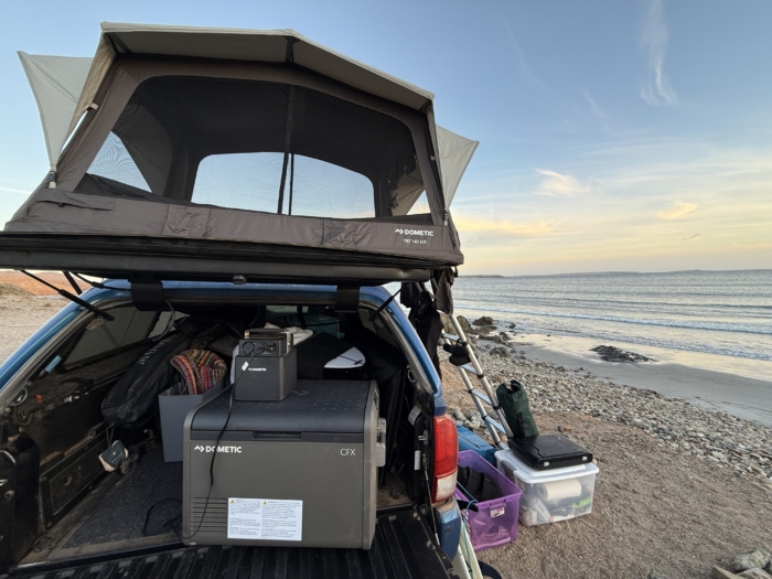 Dometic CFX 55 in back of truck bed inside topper with beach in view 