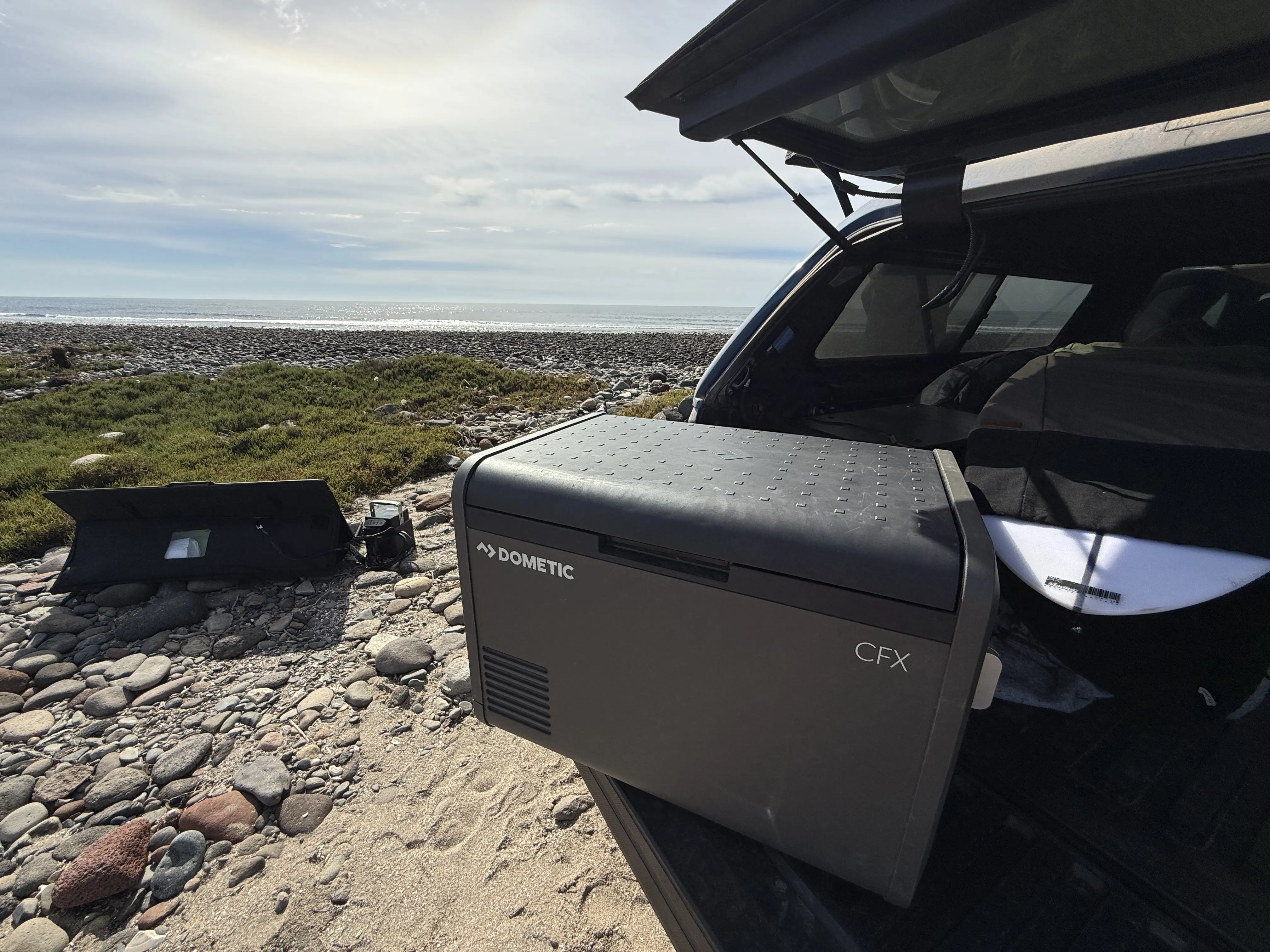 Dometic CFX 55IM Electric Cooler with surfboard and solar panel in background