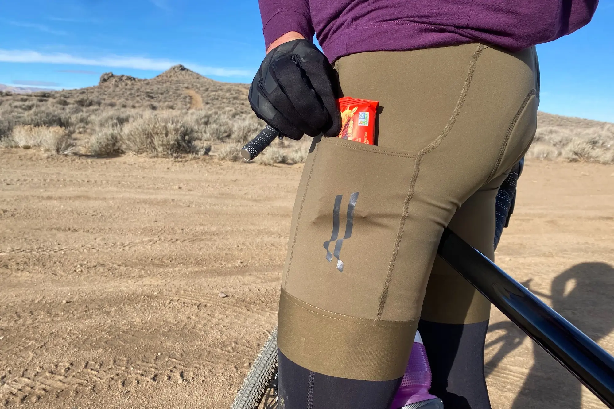 Pulling a snack out the cargo pocket on the Le Col ARC Cargo Bib Shorts