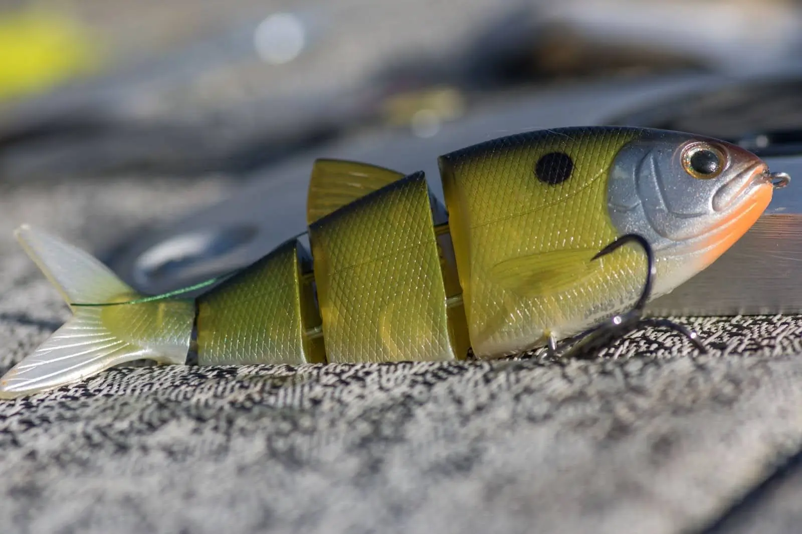 A green and yellow segmented fishing lure designed for a natural swimming motion