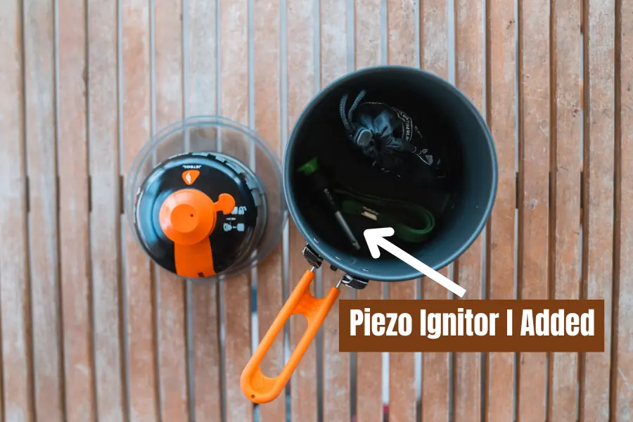 A top-down view of the Jetboil Stash stove system, showing its nesting design with a fuel canister and added piezo ignitor stored inside the pot