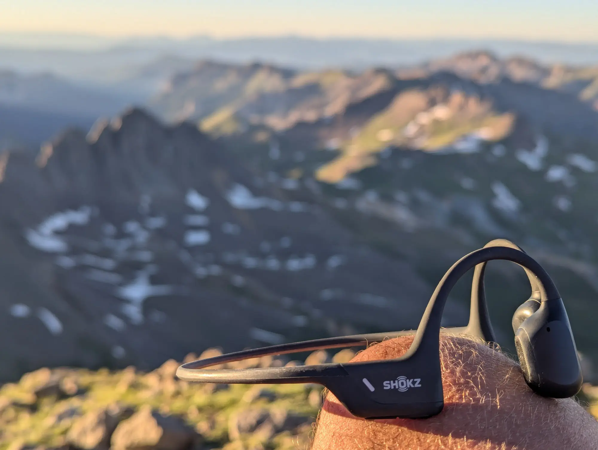 The Shokz headphones balanced on the authors knee, showing how low profile they are