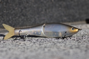 A segmented, lifelike swimbait with a shimmering body and treble hooks, designed to mimic a baitfish