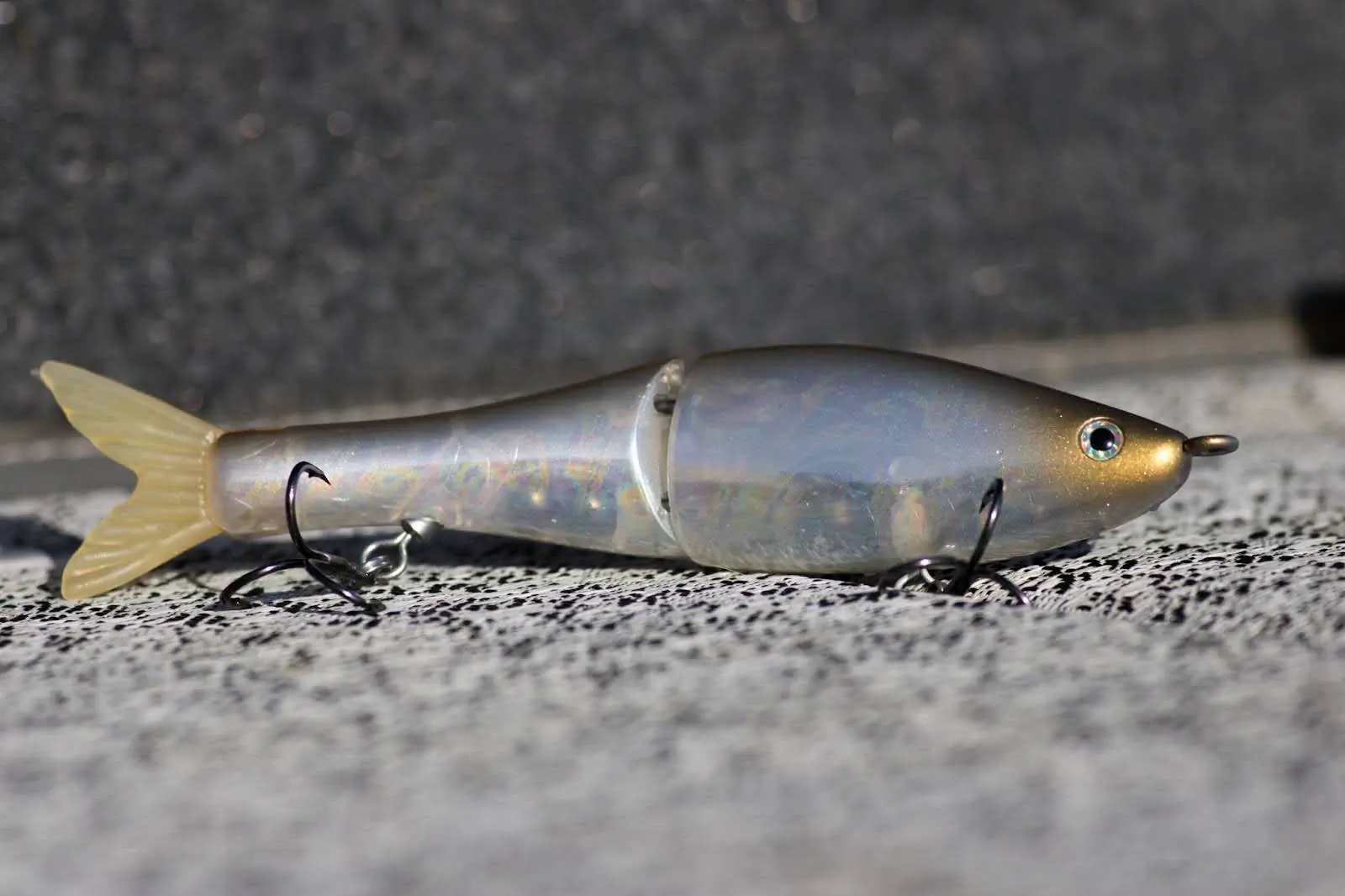 A segmented, lifelike swimbait with a shimmering body and treble hooks, designed to mimic a baitfish