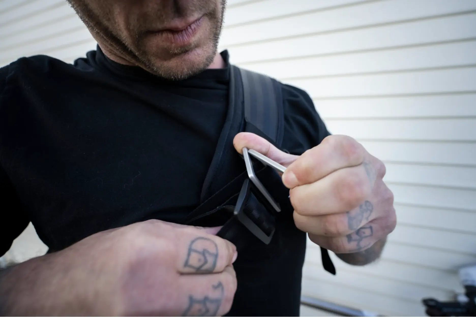 a cyclist adjusts the chunky metal buckle of the cross strap on the monty