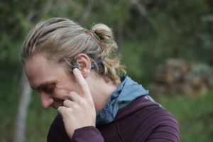 A runner adjusts the volume on the Shokz OpenRun Pro headphones