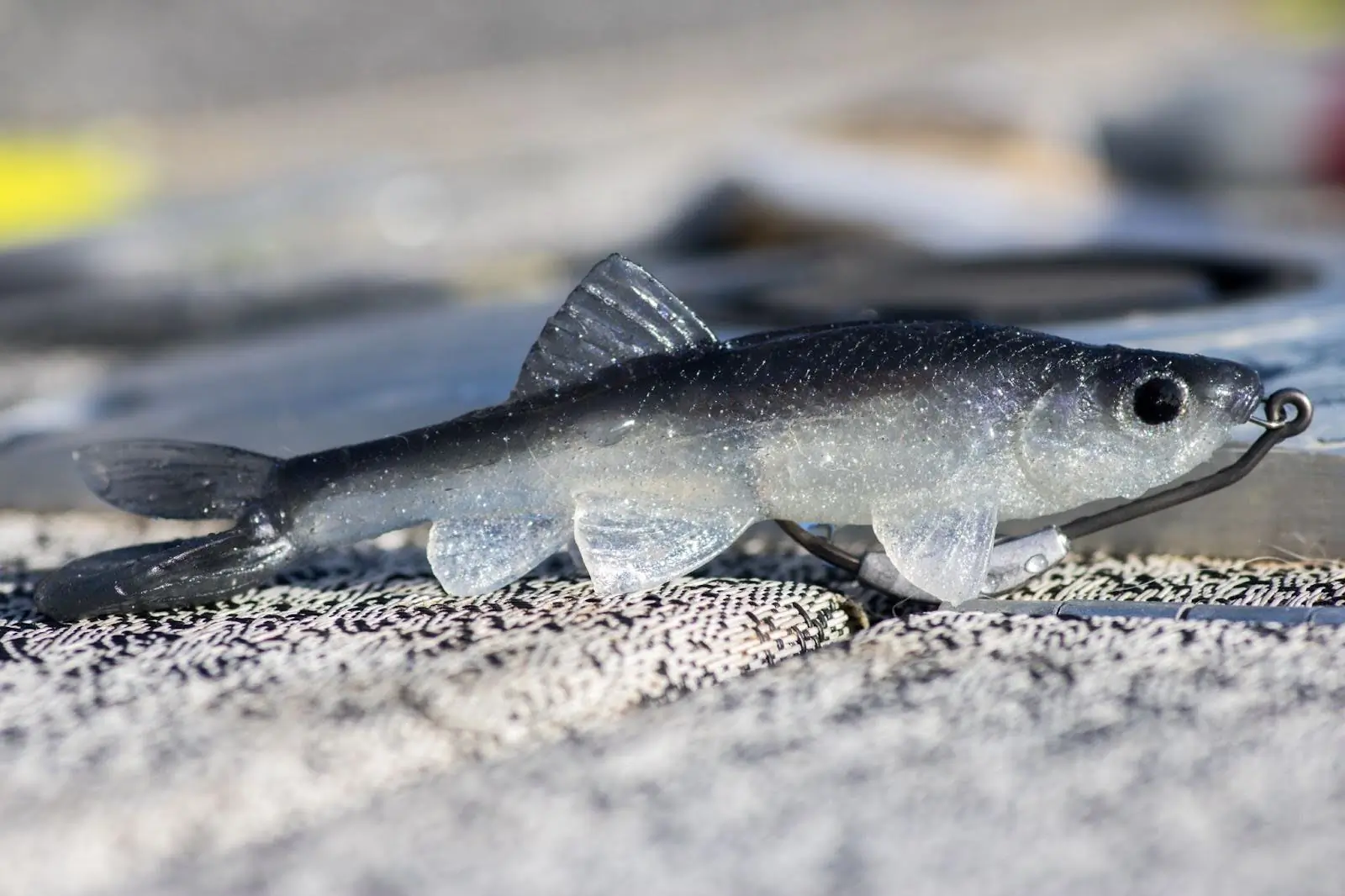 A realistic soft plastic lure shaped like a baitfish, with a hook ready for action