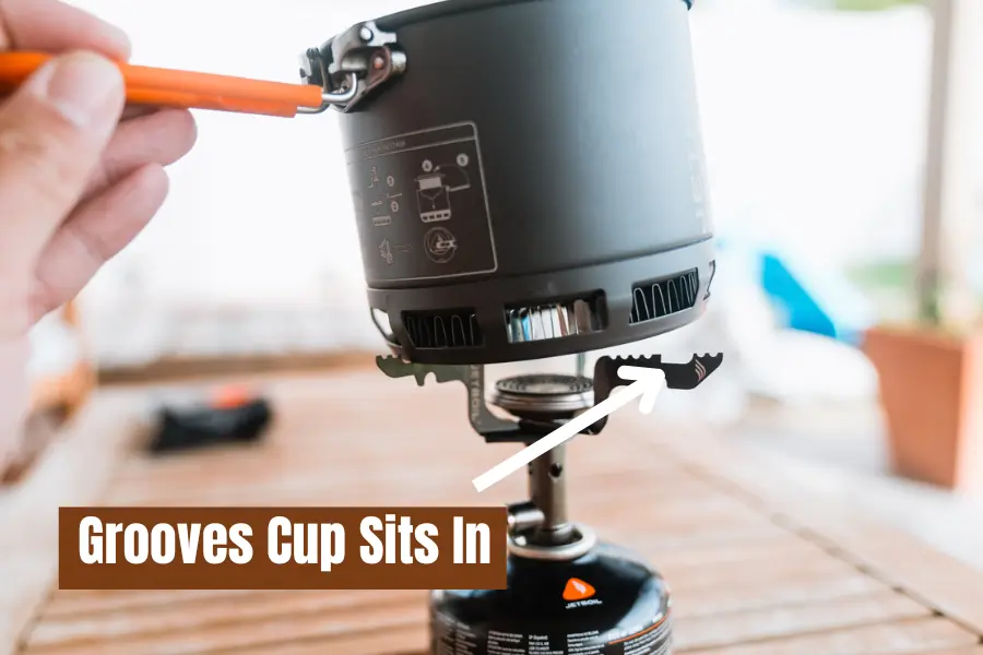 A close-up of the Jetboil Stash stove with the pot being placed onto the burner, highlighting the grooves where the pot sits for stability