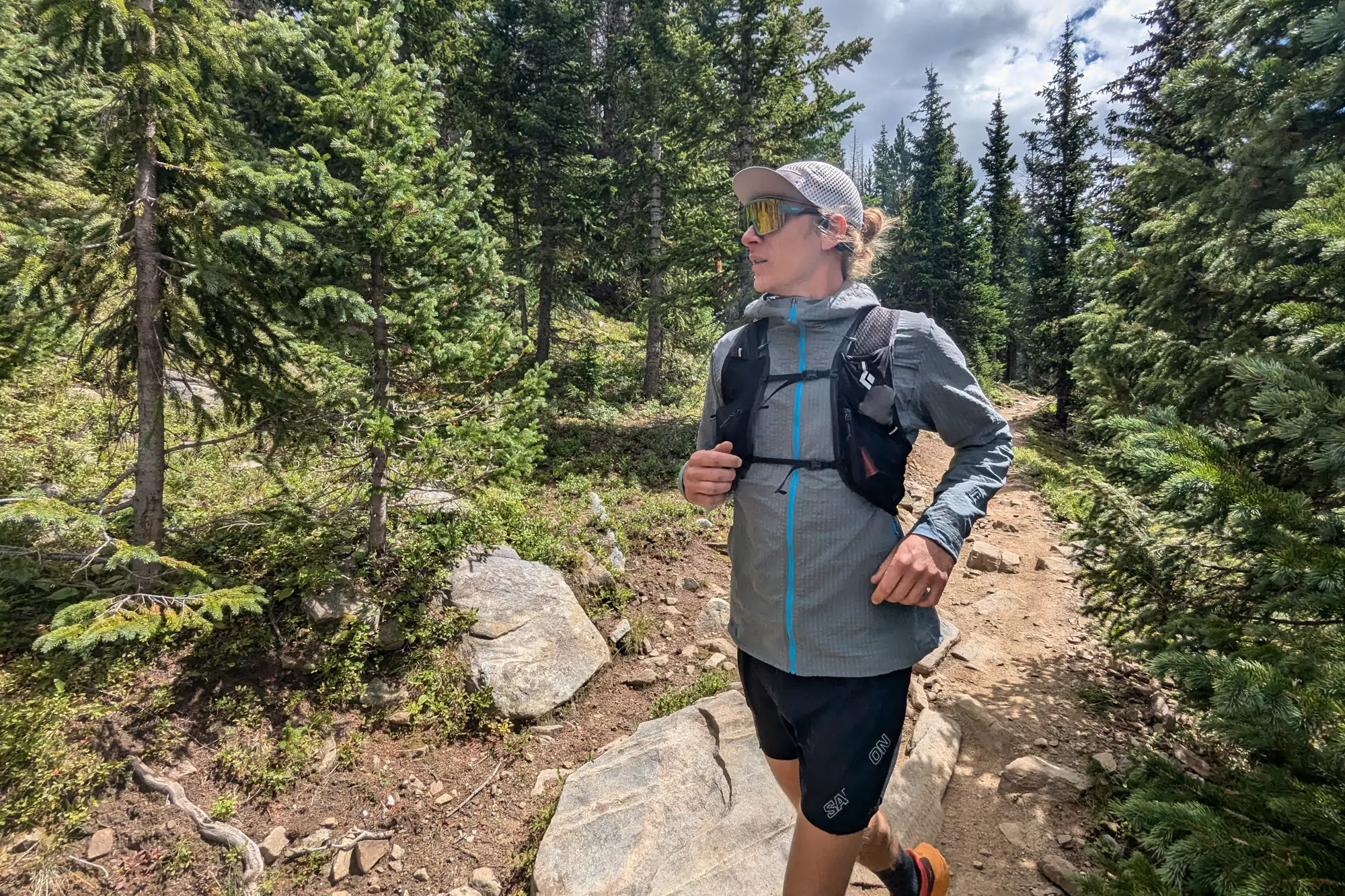 a runner moves through a low-alpine forest while wearing the headphones