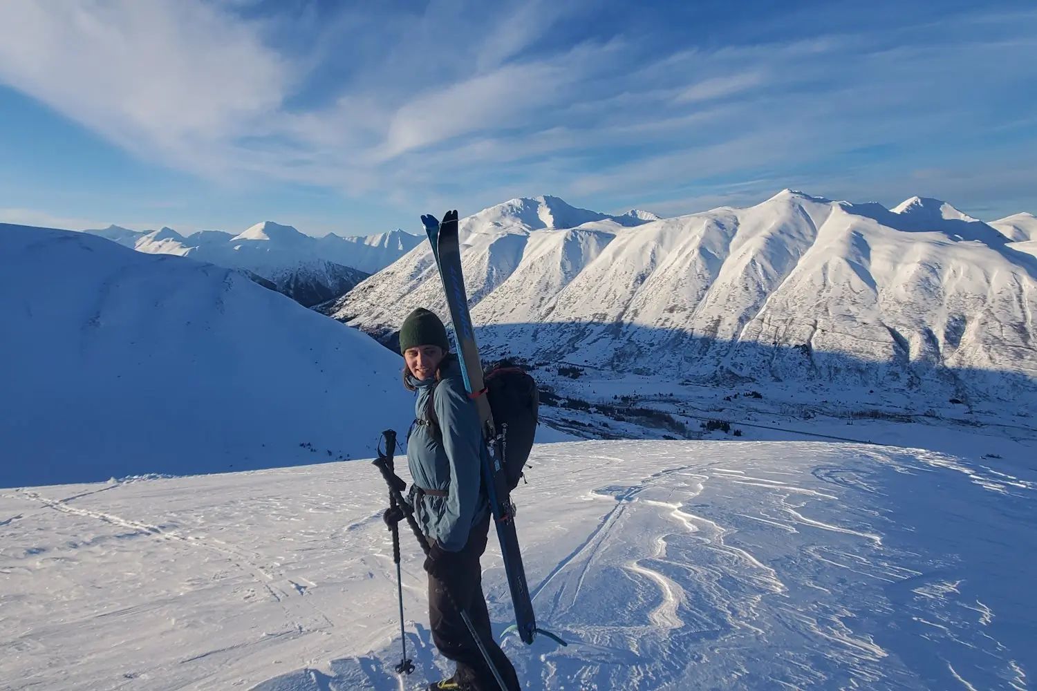 A skier wearing a backpack with skis