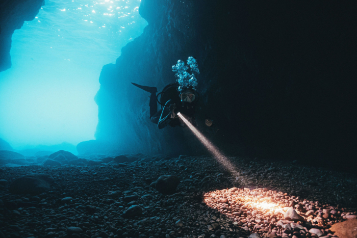 A,Scuba,Diver,Exploring,The,Underwater,Reefs,By,Illuminating,The