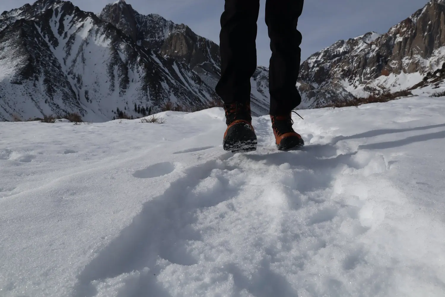 A close-up view of a person walking on snow wearing Vasque St. Elias hiking boots,