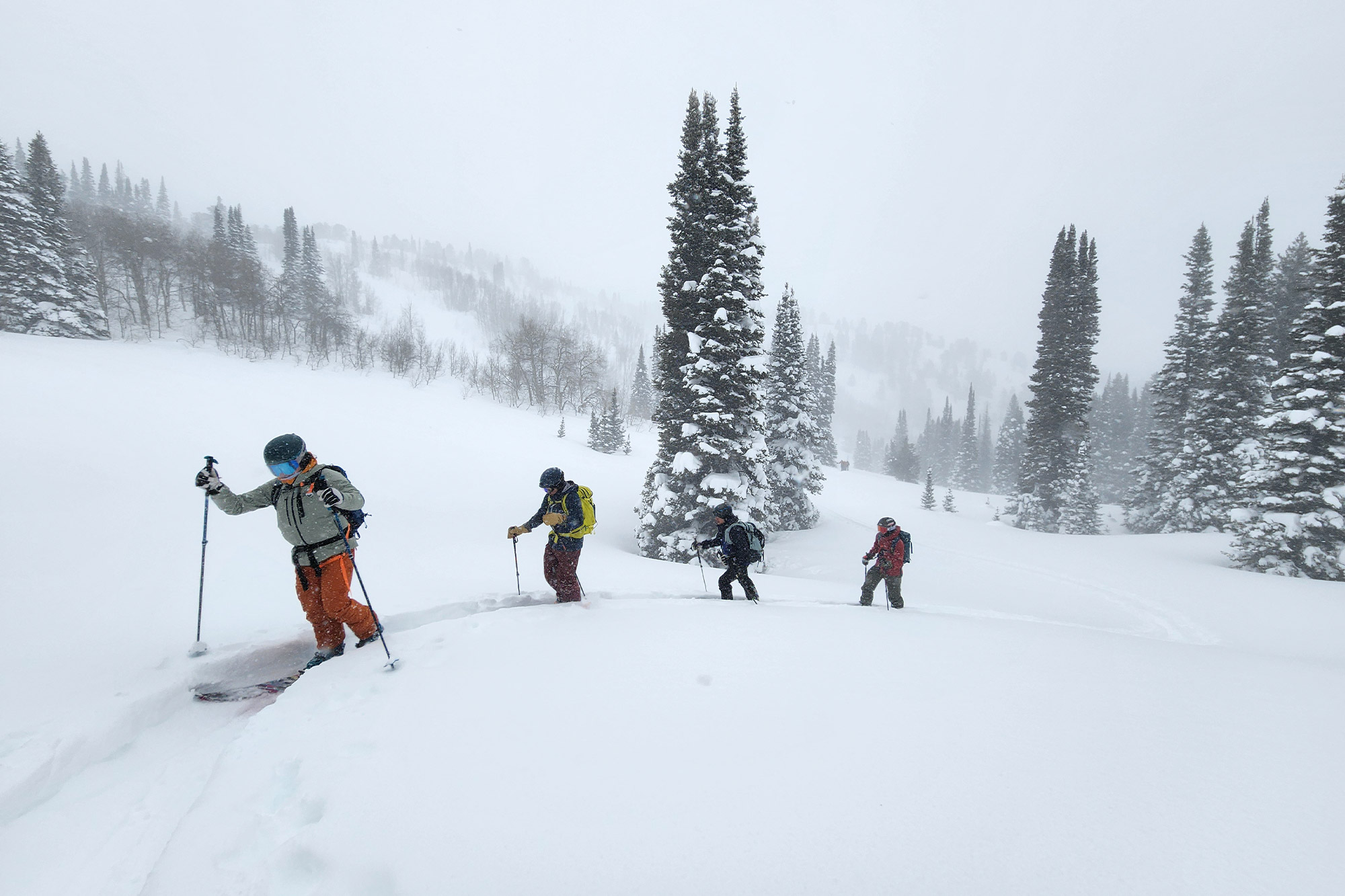 A group of skiers ascending a snowy mountain ridge in deep powder conditions